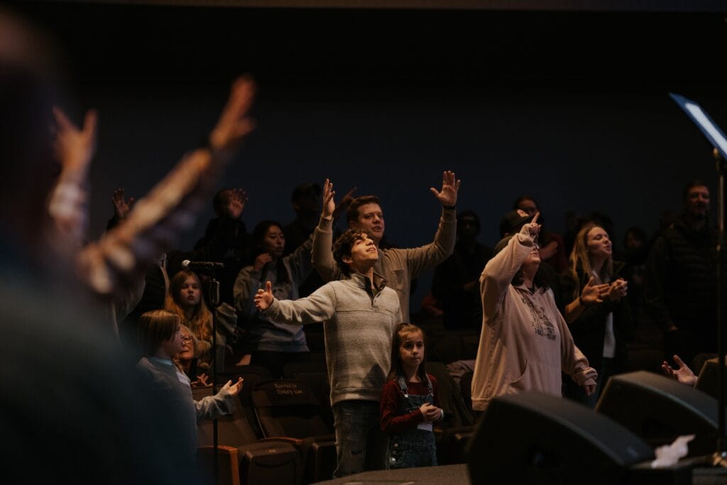 A group of people raising their hands in worship, seeking revival, at Westgate Chapel, a nondenominational church in Edmonds, WA.